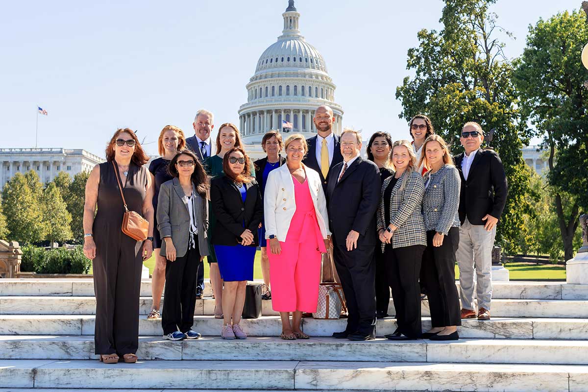 A group of Washington Conference attendees pose for a picture on steps of the U.S. Capitol building.