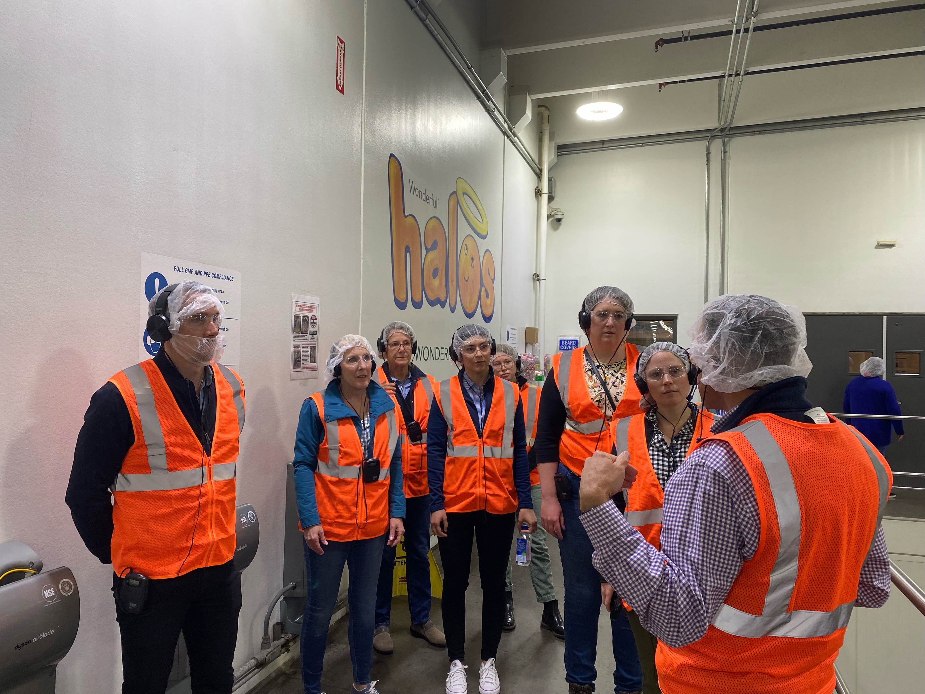 2022 cohort participants dressed in safety vests and hair-nets visit The Wonderful Company